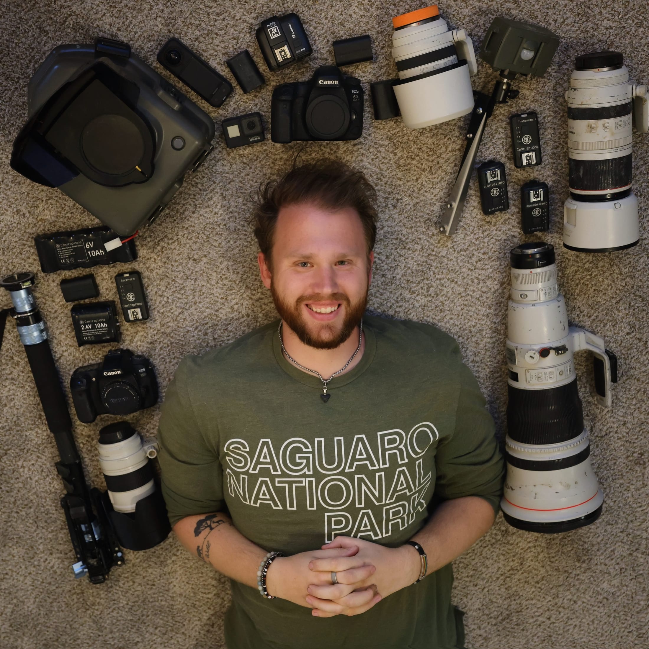 Kyle Rohlfing lying among his wildlife photography camera gear and telephoto lenses